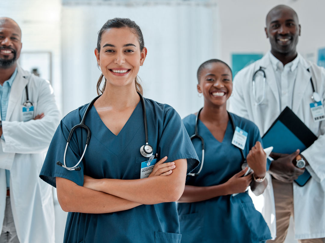 A group of diverse people working and smiling together in a library or office setting.