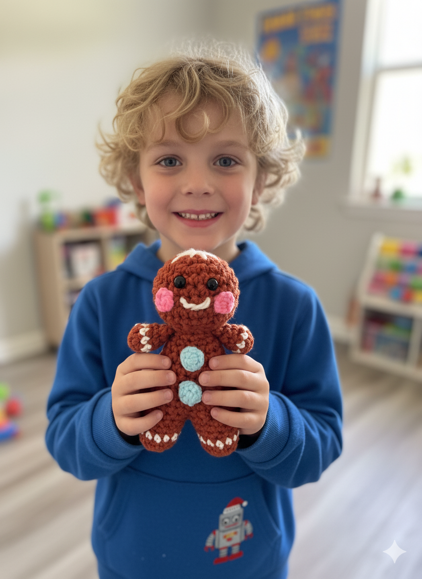 A smiling boy holding a handmade crochet gingerbread man.