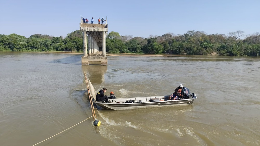 Equipes de mergulho dos bombeiros utilizam barco para vistoriar área onde caminhão caiu.