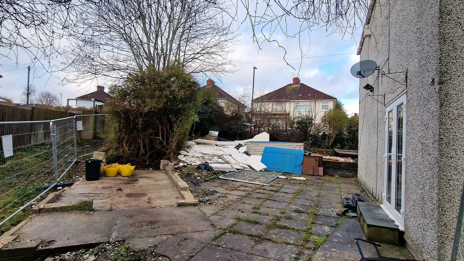 Building an extension in winter: a fenced Brislington plot in February, rubble piled beside the neighbouring house