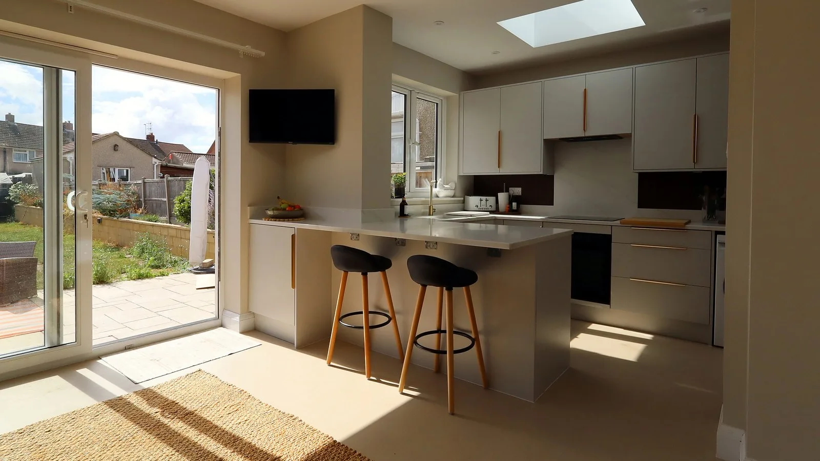 Replace conservatory with extension: finished open-plan kitchen with a rooflight and sliding doors to the garden in Kingswood
