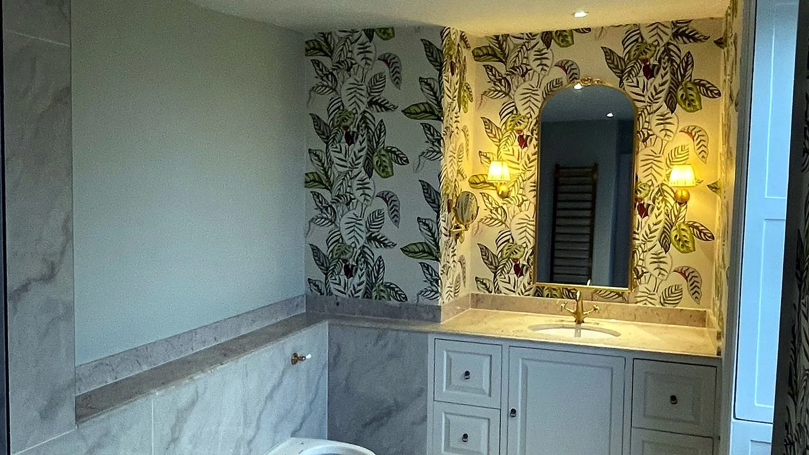 Ensuite renovation in a Georgian house: painted vanity, arched mirror between wall lights and leaf wallpaper