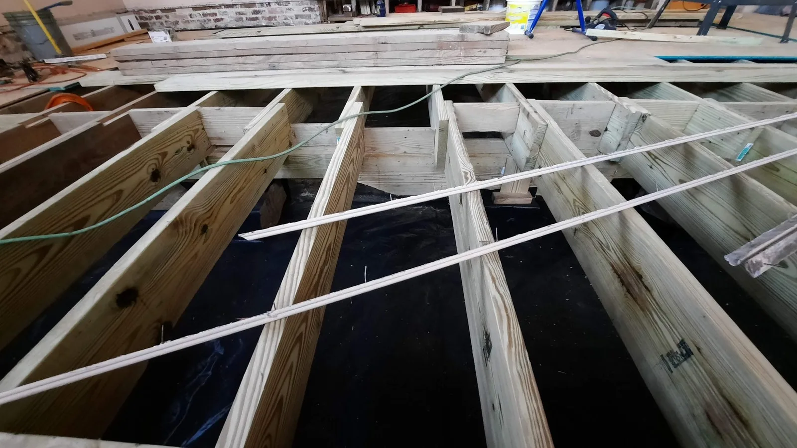 Structural repairs to an old house: new timber floor joists being fitted over a membrane