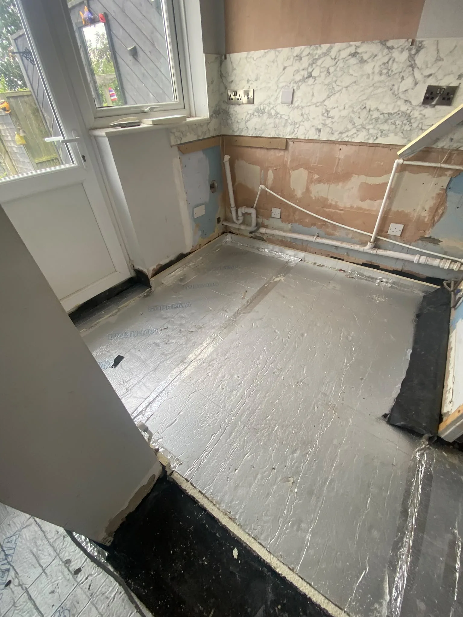 Foil-faced insulation boards laid across a dug-out kitchen floor during subsidence repairs