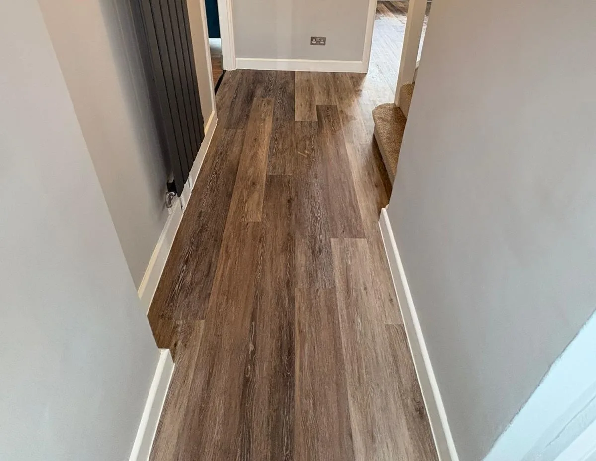 Finished hallway with wood-effect LVT flooring and a black vertical radiator