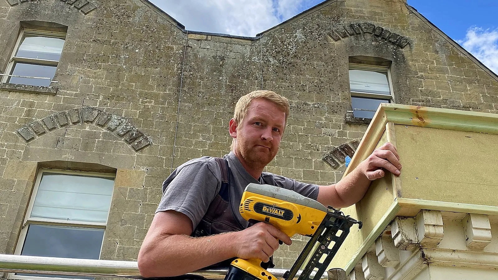 TrustMark registered builder Wilson & Cole: one of the founders with a nail gun on the scaffold of a stone house