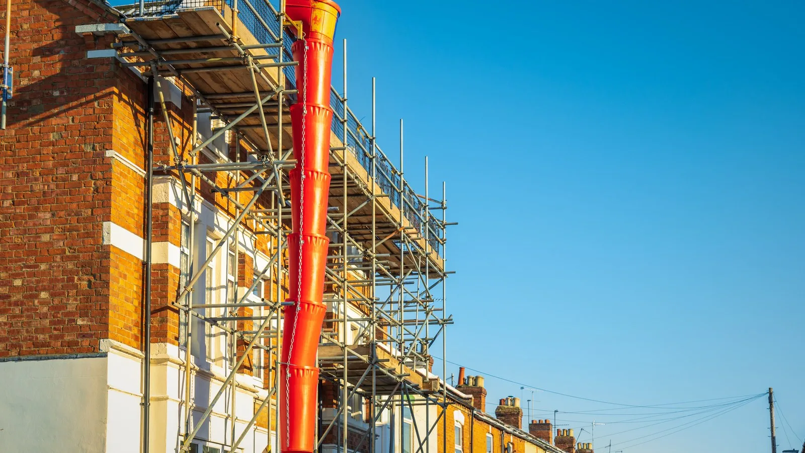 Two storey extension cost guide: scaffolding and a rubble chute on a red-brick terraced house