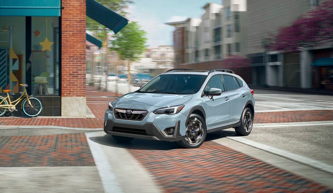 vue 3/4 avant d'un VUS Subaru Crosstrek 2022 gris tournant sur une intersection en ville