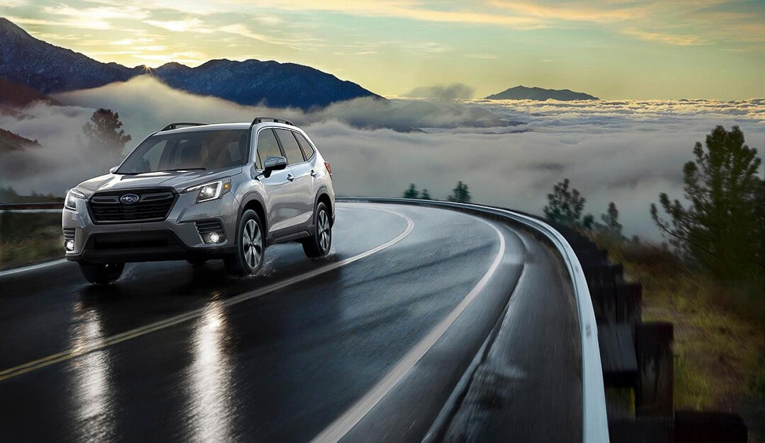 Un VUS Subaru Forester 2022 roulant sur une route au bord des montagnes et nuages