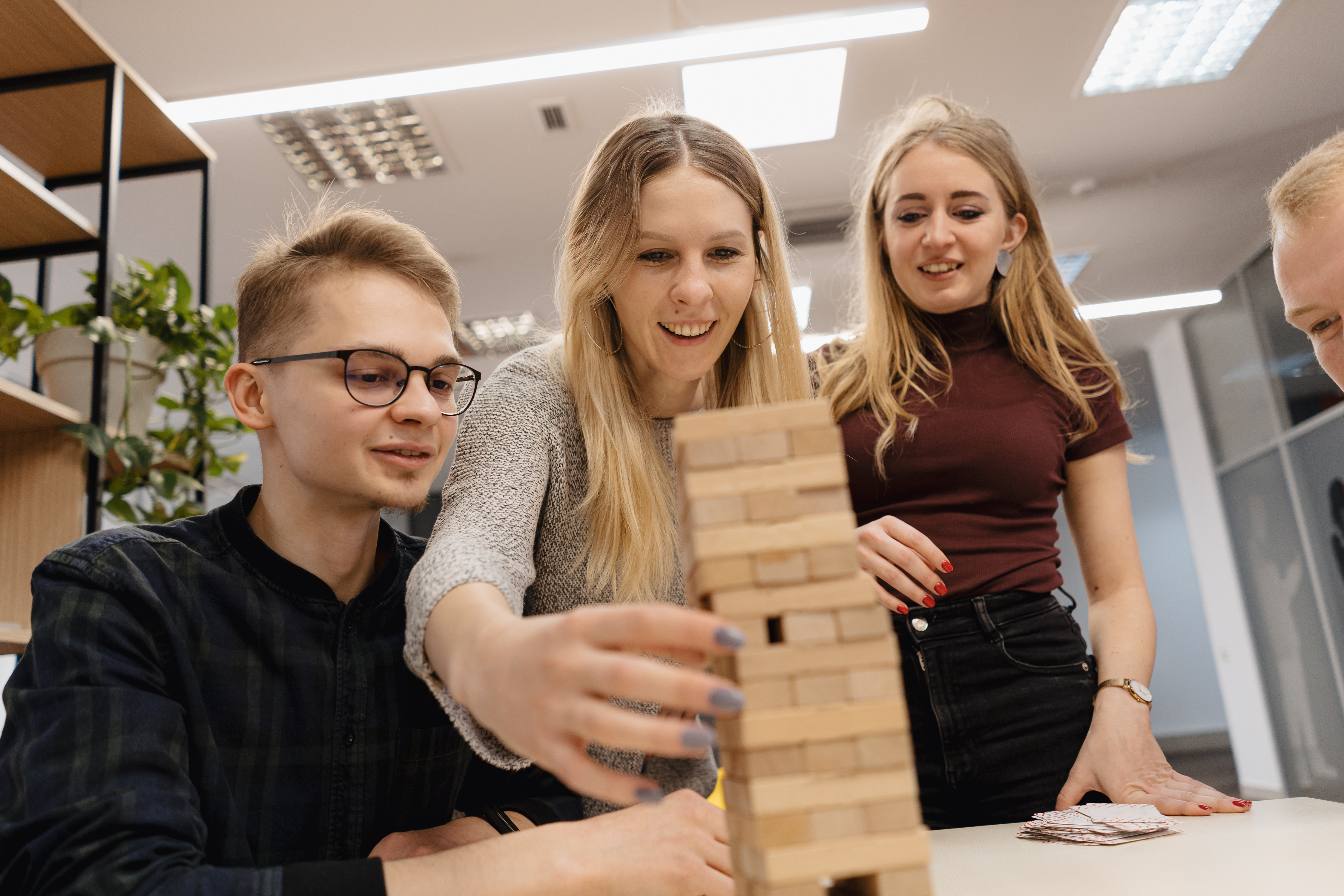 Trei copii si un adult care se joaca Jenga