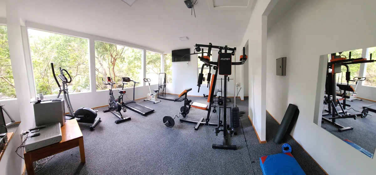 Gimnasio bien equipado en la instalación. Máquinas de pesas, cintas de correr y vistas al exterior.