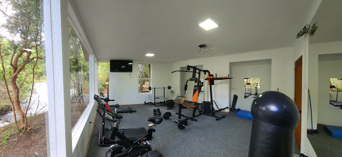 Gimnasio bien equipado en [Prueba 1], con vistas a la naturaleza. Área común para el bienestar.