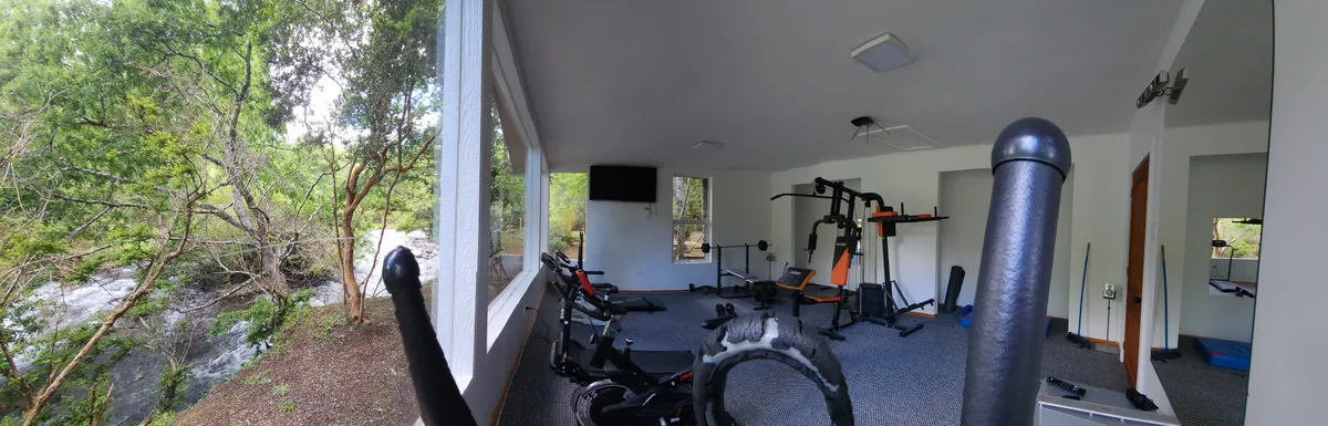 Gimnasio con vista al río en Prueba 1. Equipo de ejercicio, pesas y luz natural.