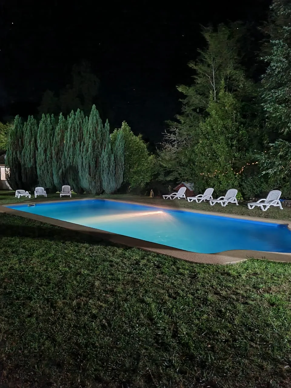 Piscina iluminada de noche en Instalación del Recinto. Relax y diversión en un entorno natural.