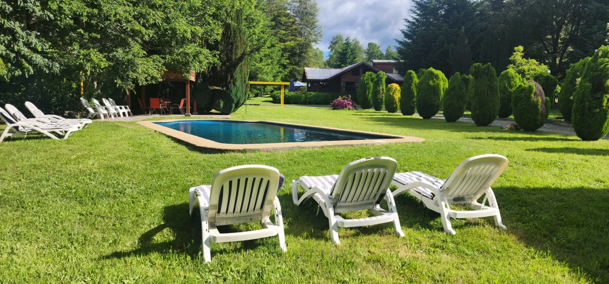 Piscina al aire libre rodeada de jardines y tumbonas en Hotel Prueba 1. Relax y naturaleza en un mismo lugar.