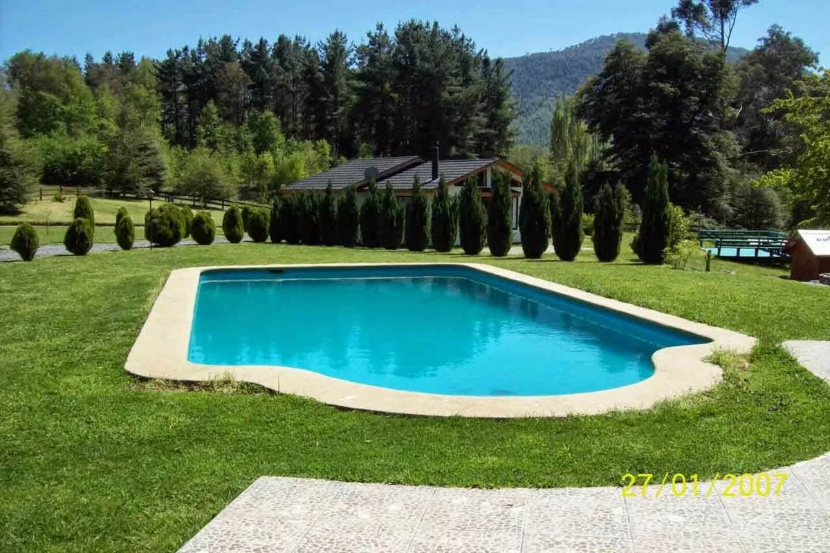 Piscina exterior con agua cristalina rodeada de césped en Instalación del recinto. Ideal para disfrutar del sol y la naturaleza.
