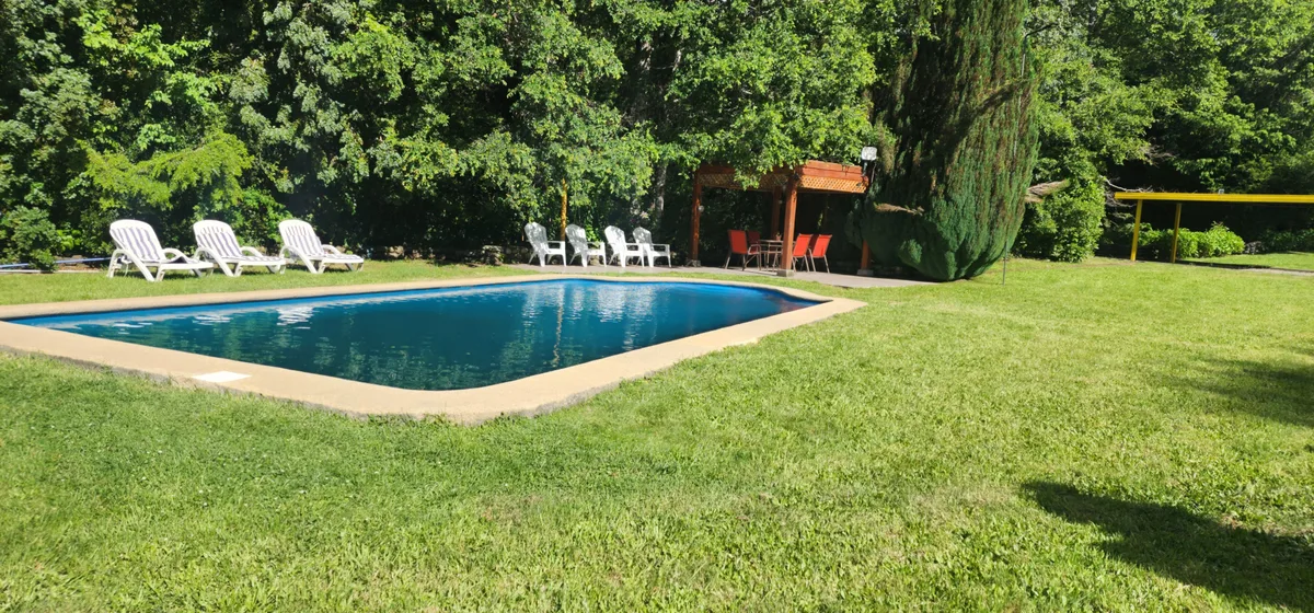 Piscina exterior rodeada de césped y vegetación en Instalación del recinto, un espacio común ideal para relajarse y disfrutar.