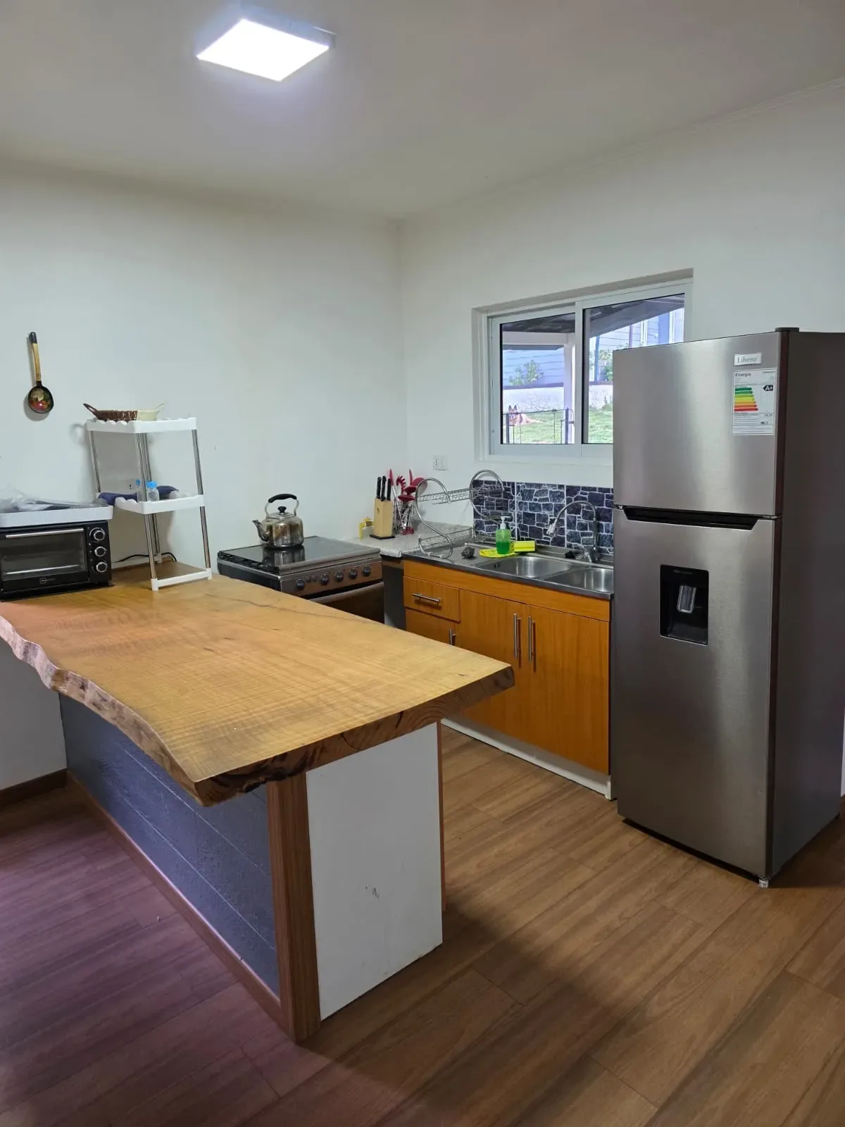 Cocina Cabaña 10 Pucón: Horno microondas, refrigerador y detalles de la encimera de madera rústica.