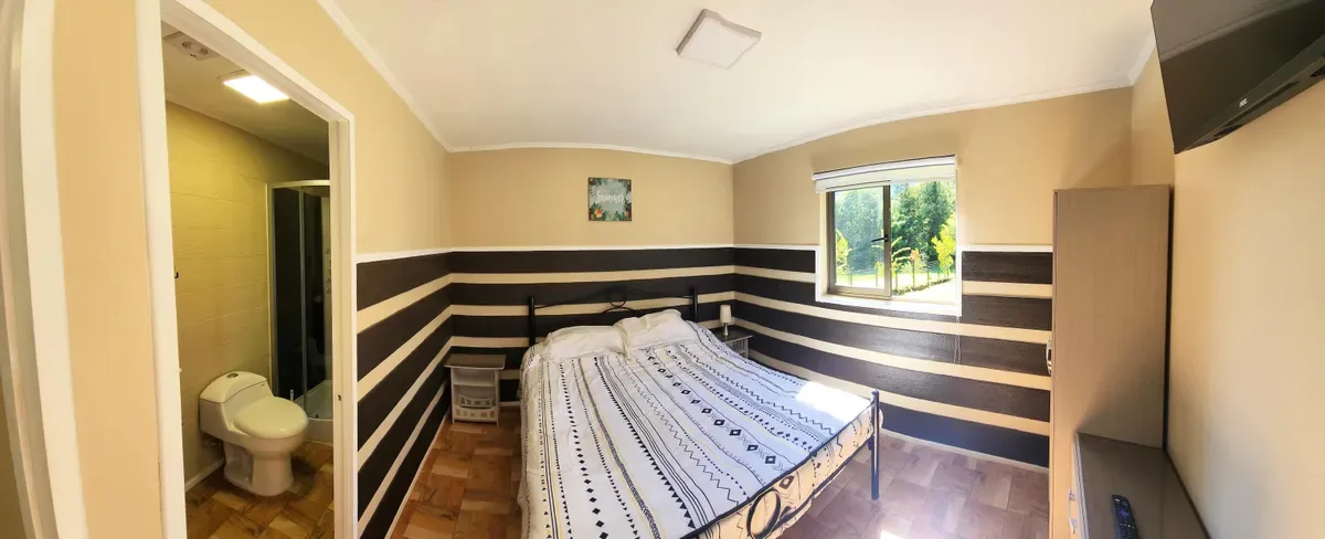 Dormitorio principal en suite, Cabaña 9, Pucón. Cama doble, baño privado, luz natural.