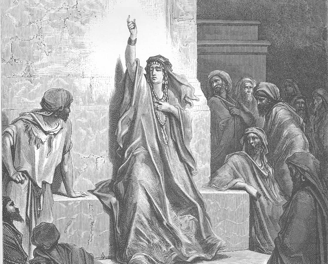 Deborah stands on the steps and lifts her hand as she speaks to the men of Israel