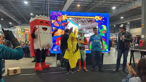 Ticão, o mascote da SuperTixs, no palco de games diante de um telão