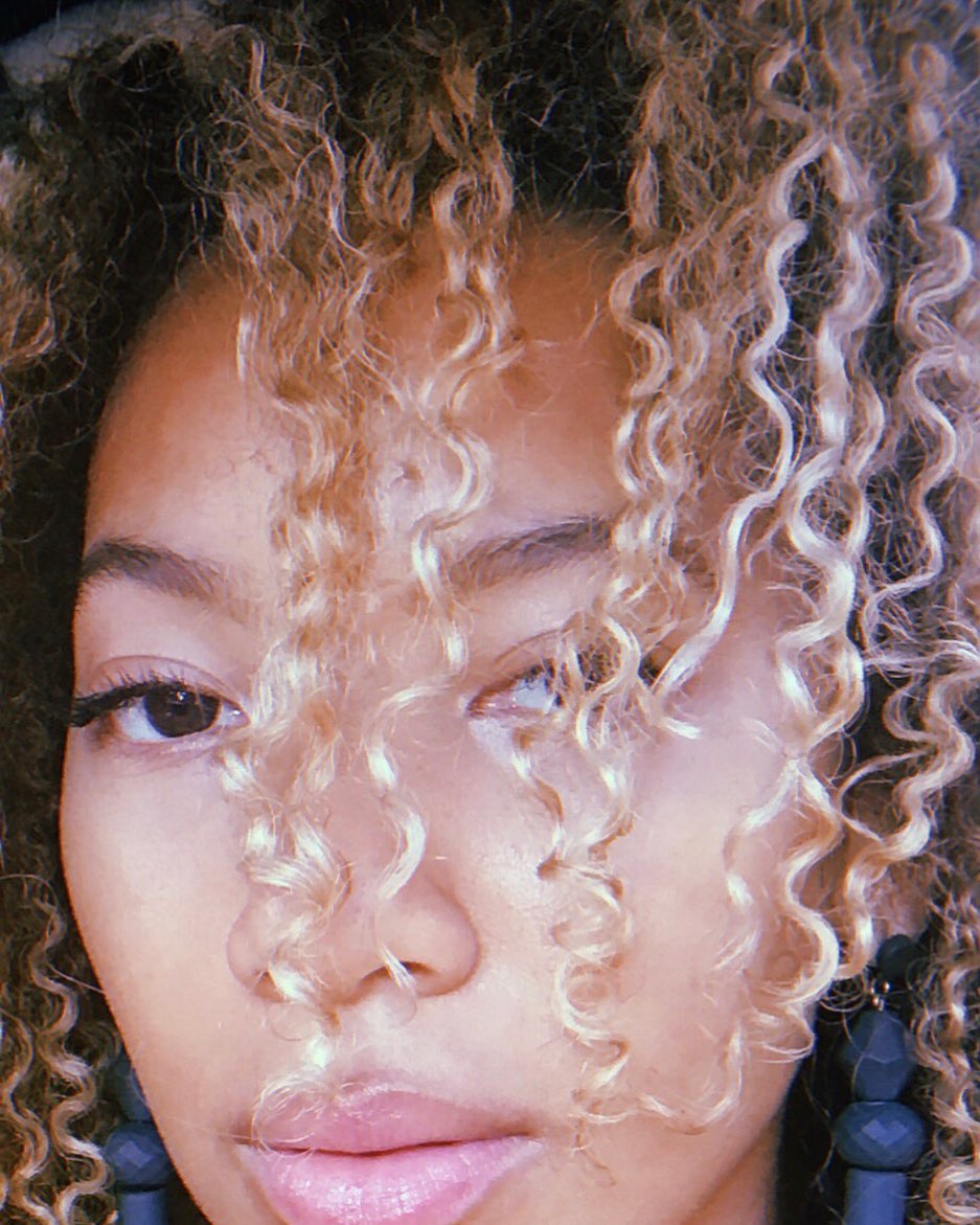 Alyssa Simone looks through her curls in a close-up selfie.