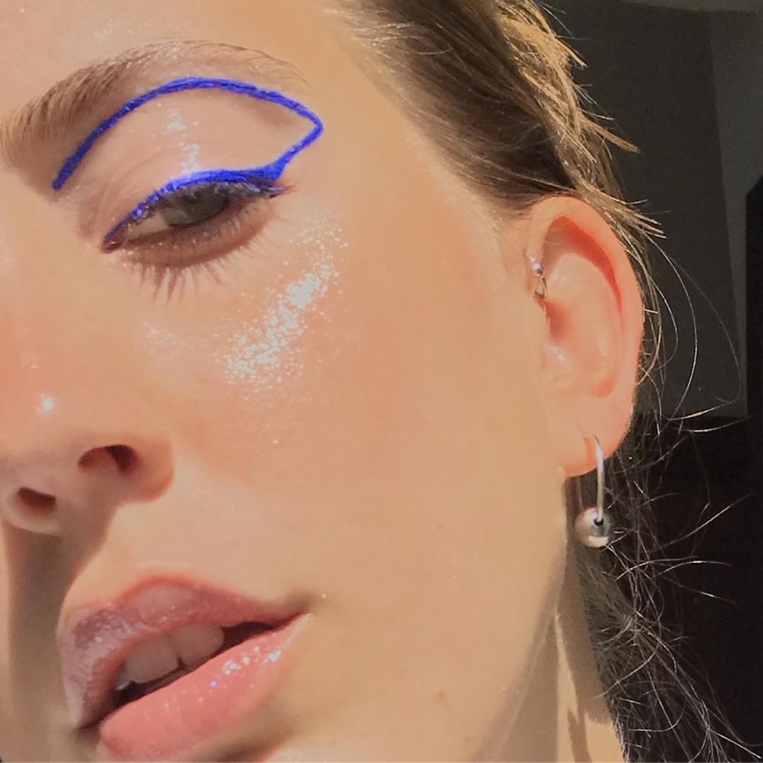 An electric blue line frames Savannah's left eyelid in a half-face selfie that shows her glowing skin.