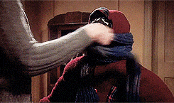 A mom wraps her child's face in multiple scarf layers.