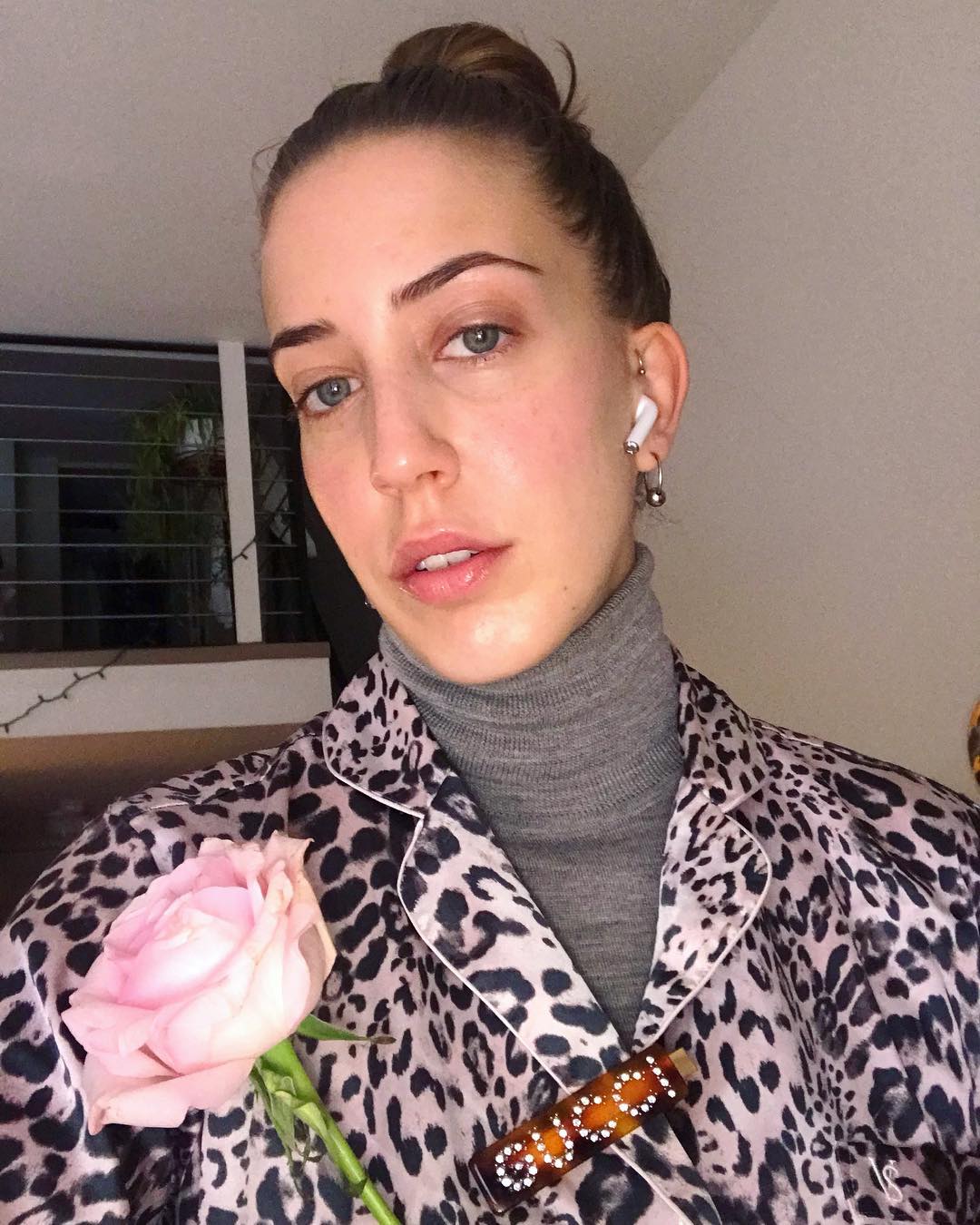 Savannah takes a selfie of her glow-y, bare skin while wearing a leopard print top over a gray turtleneck.