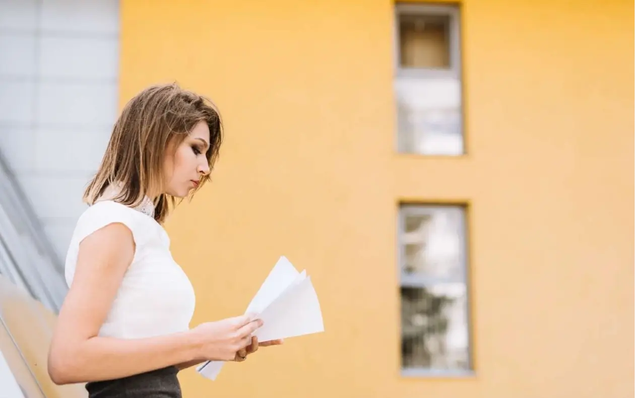 Zabrinuta žena sa dokumentima ispred austrijske administrativne zgrade