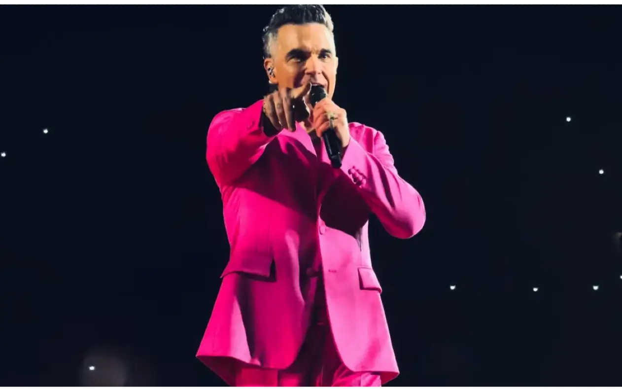 Robbie Williams nastupa na stadionu Ernst Happel u Beču, okružen svetlima i publikom.
