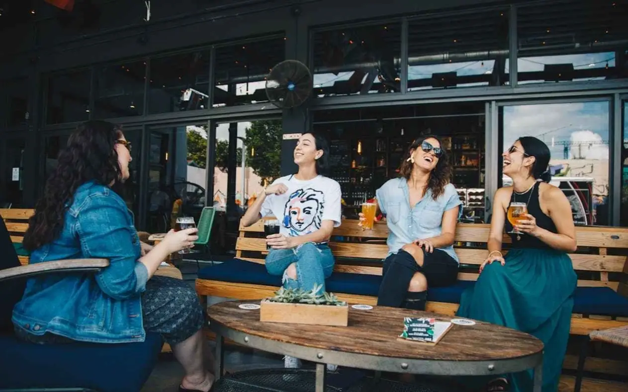 Nasmejani ljudi sede u kafiću i pričaju dok piju pivo