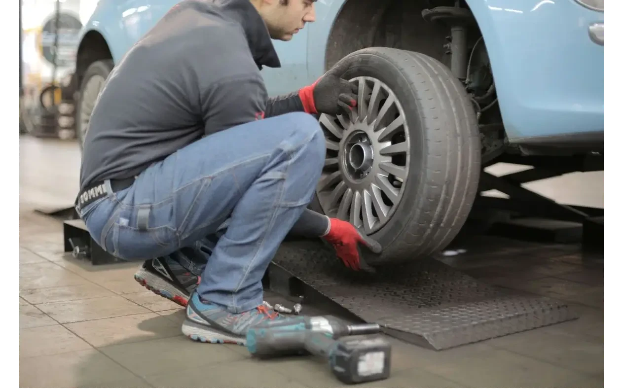Mehaničar postavlja točak na automobil u radionici