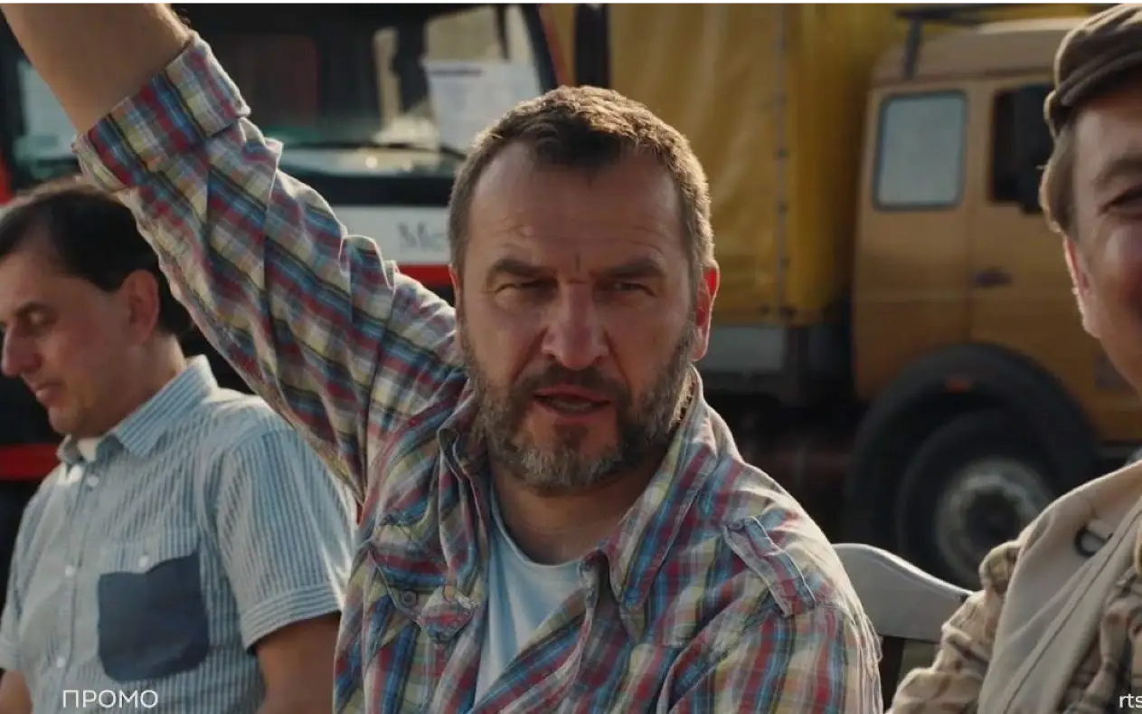 Scena iz serije "Kamiondžije" Glumci iz serije "Kamiondžije" sede na otvorenom, jedan od njih diže ruku, dok drugi osmehnuto gleda u kameru.