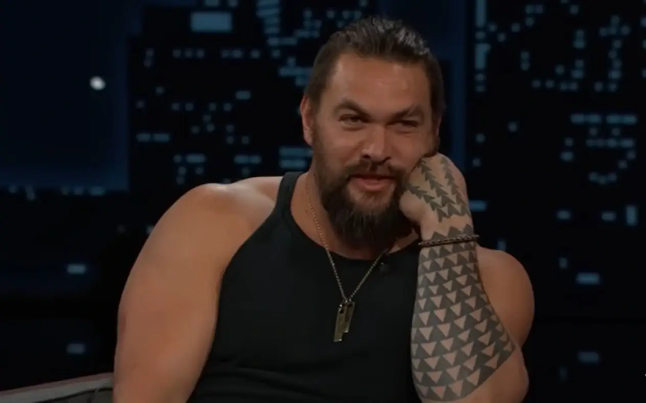 Jason Mamoa u TV emisiji Jasona Mamoa u crnoj majici sa naslonjenom rukom