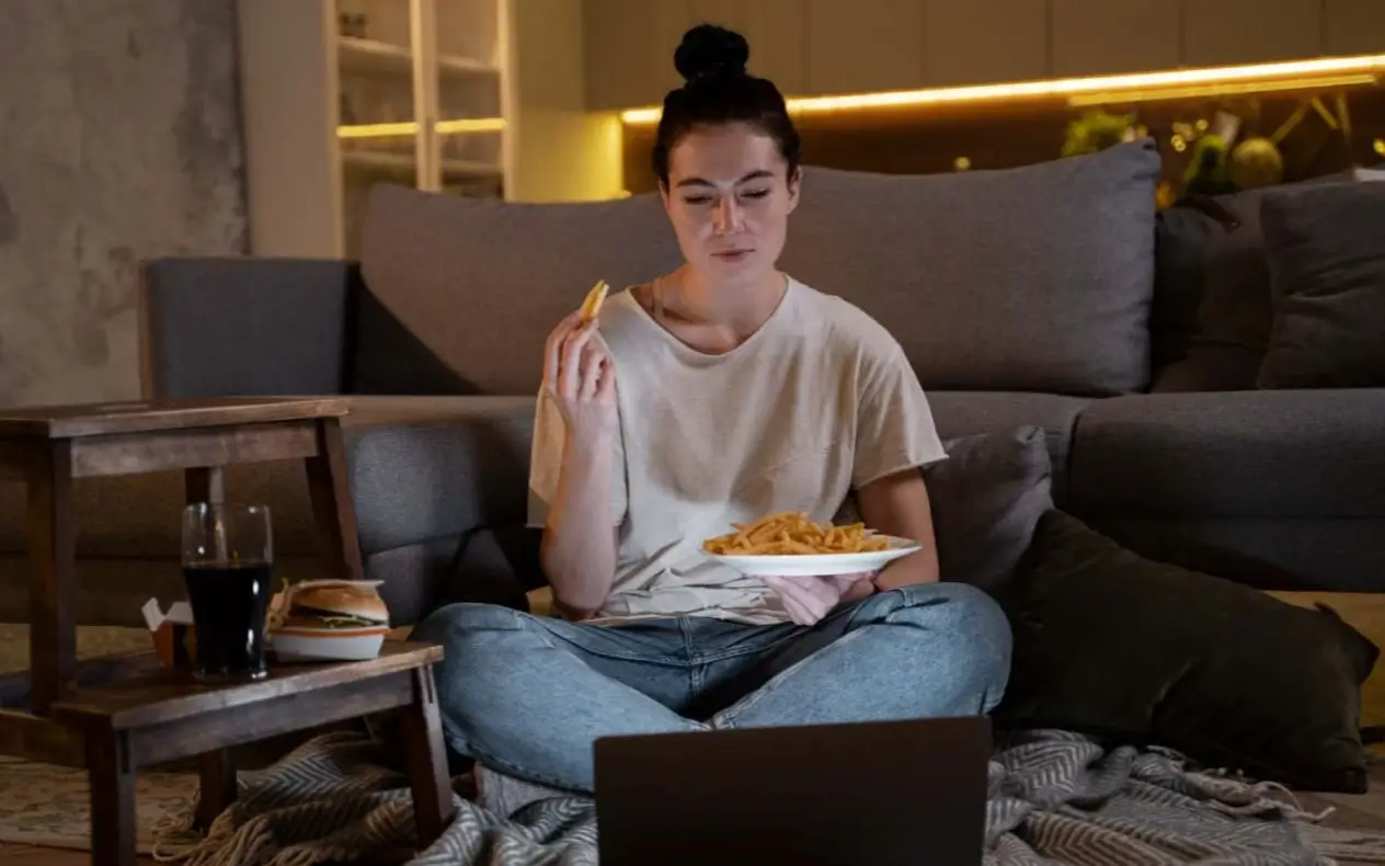 Devojka gricka isped laptopa dok gleda film
