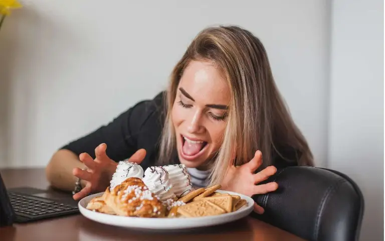 Devojka gleda u tanjir pun slatkiša