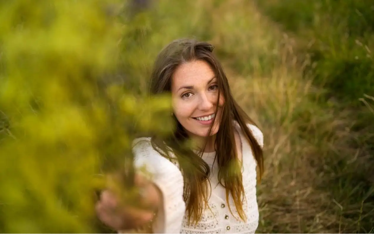 Žena srednjih godina nasmejana u prirodi, simbolizuje novi početak nakon bolesti.