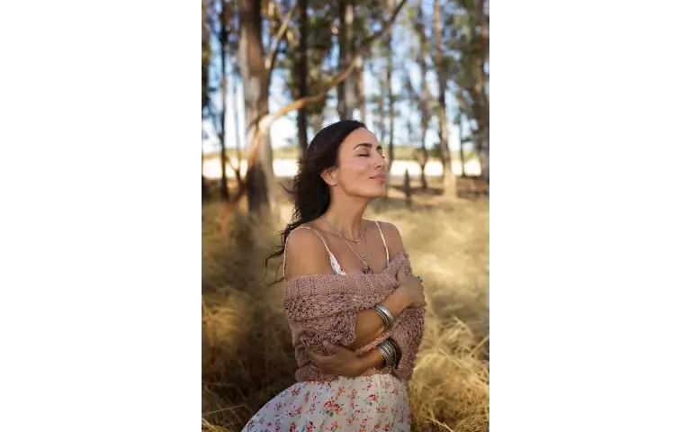 Žena nasmejana uživa u prirodi sa osmehom na licu