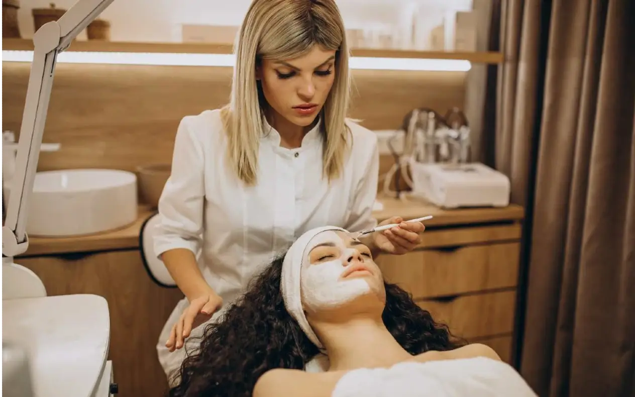 Žena uživa u tretmanu lica egzozomima u modernom kozmetičkom salonu, ležeći opušteno dok kozmetičarka koristi dermapen aparat