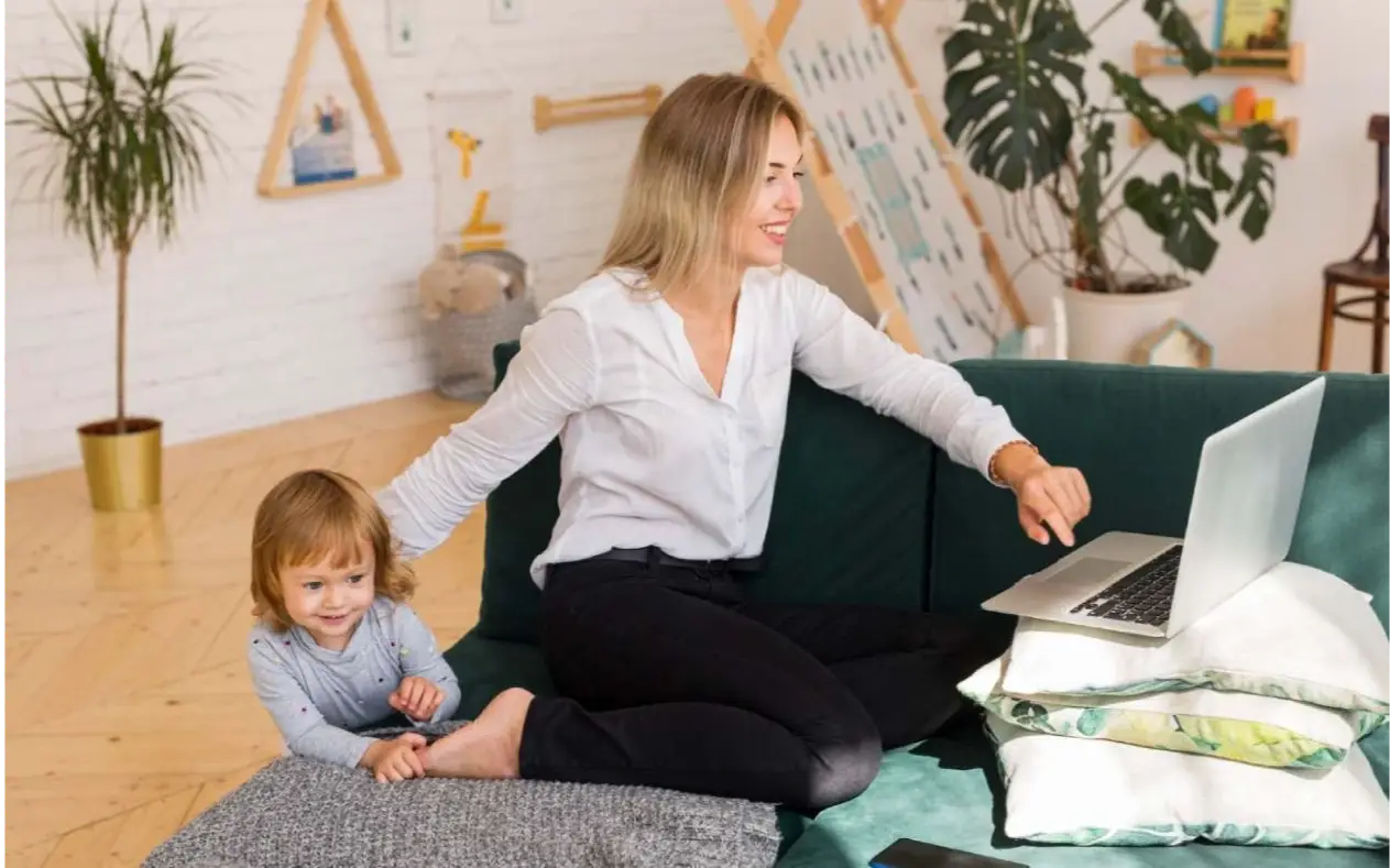 Mama balansira posao i roditeljstvo, dete sedi pored nje dok koristi laptop