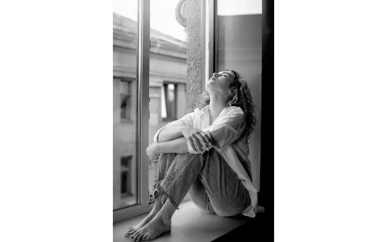 Žena pored prozora: crno-bela Žena usamljena i sama pored prozora