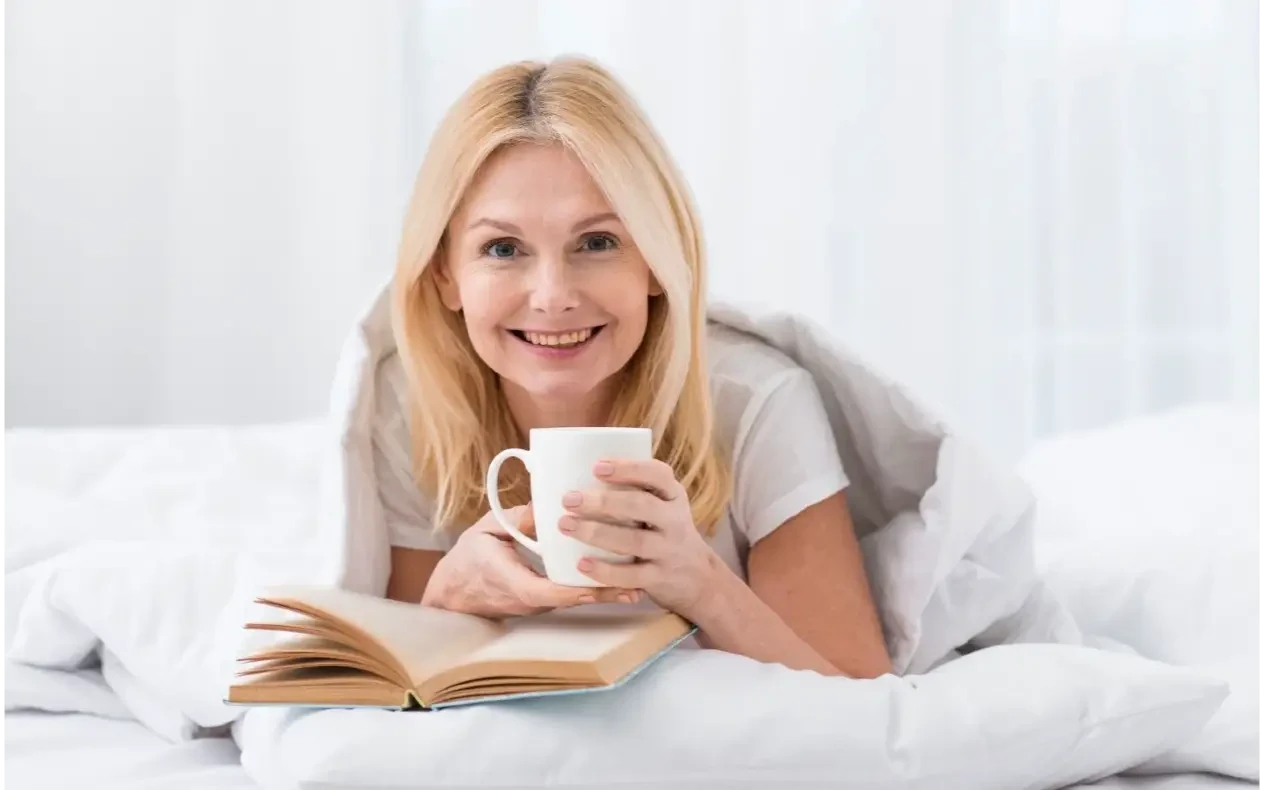 Menopauza i san – večernja rutina za žene posle 50. godine Žena starija od 50 godina opušta se uz čaj i knjigu tokom večernje rutine koja može doprineti kvalitetnijem snu u menopauzi.