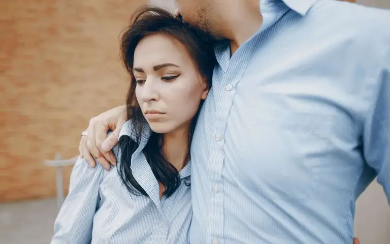 Tužna devojka Tužna devojka u žagrljaju muškarca dok šetaju ulicom i on je ljubi u glavu