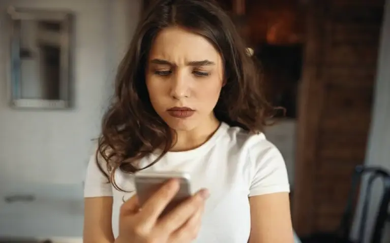 Devojka tužno gleda u telefon Devojka tužno gleda u telefon nakon poruke o raskidu koju je dobila