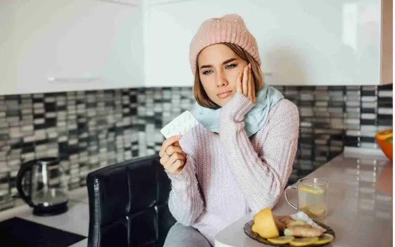 Devojka sa prehladom Prehlađena devojka gleda u lekove