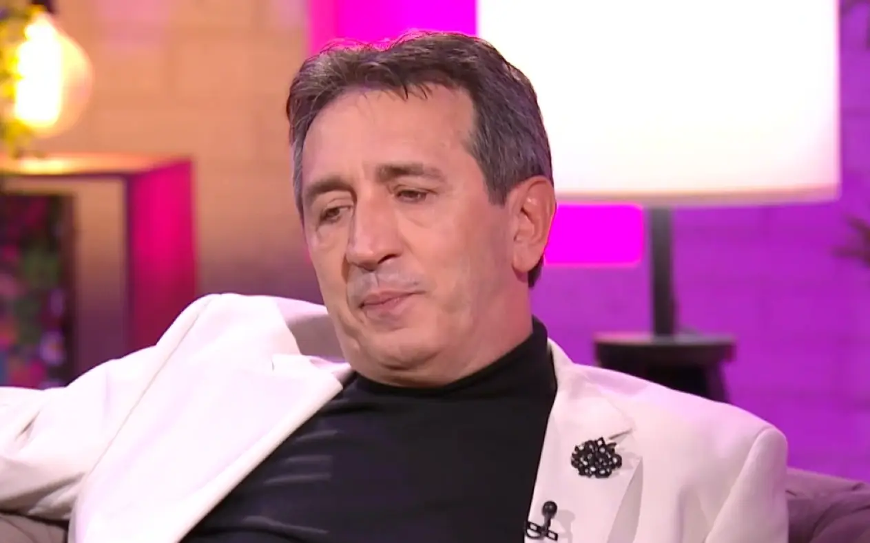 Žika Jakšić u TV emsijii Žika Jakšić u belom sakou i crnoj majici zamišljenog pogleda