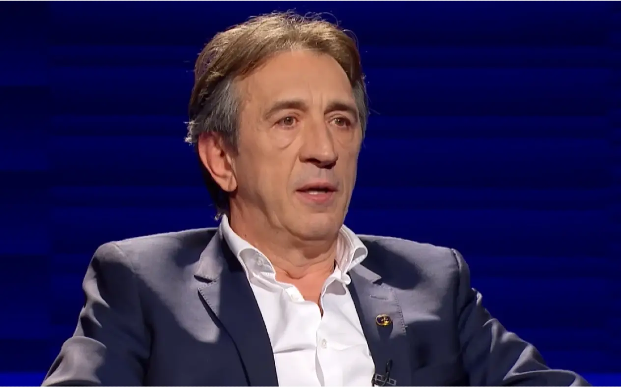 Žika Jakšić u teget odelu i beloj košulji sa blagim osmehom na licu tokom gostovanja u emsijii