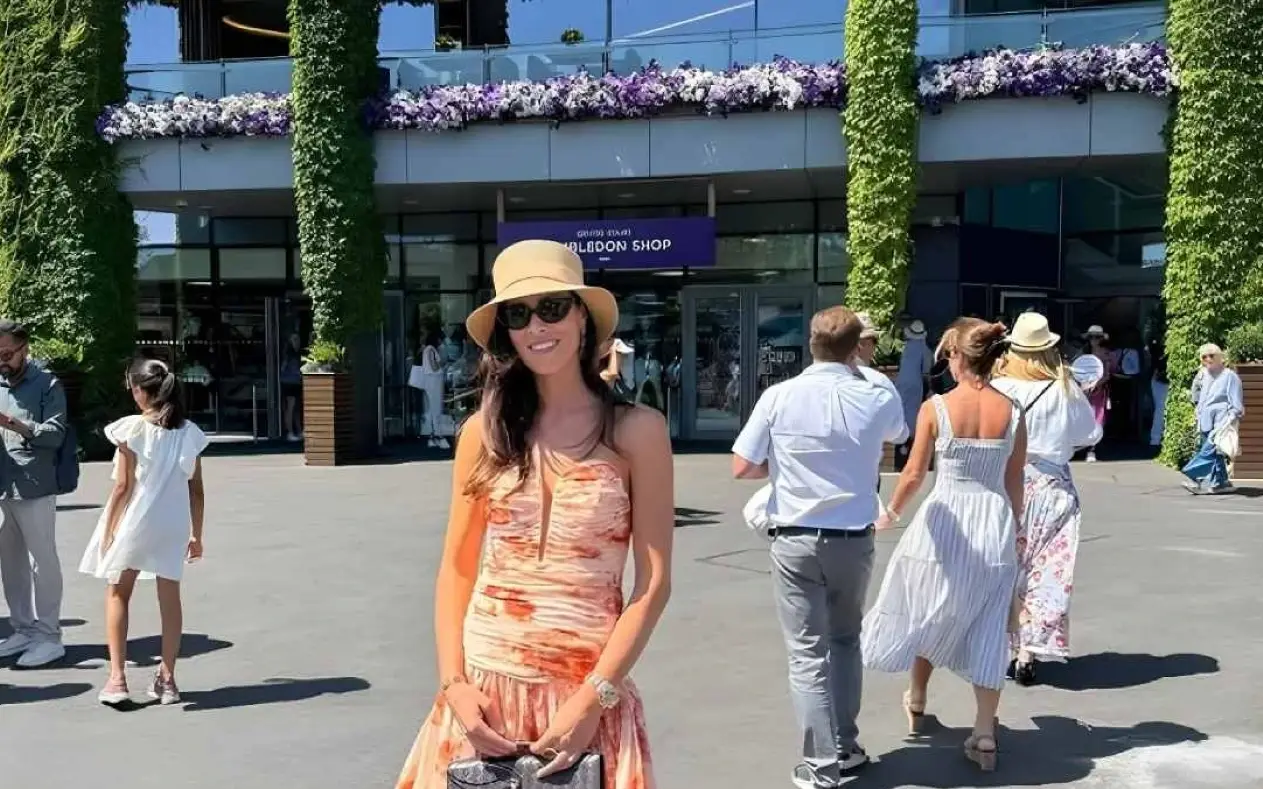  Ana Ivanović ispred Centralnog terena na Vimbldonu u elegantnoj letnjoj haljini sa cvetnim motivima, šeširom i sunčanim naočarima.