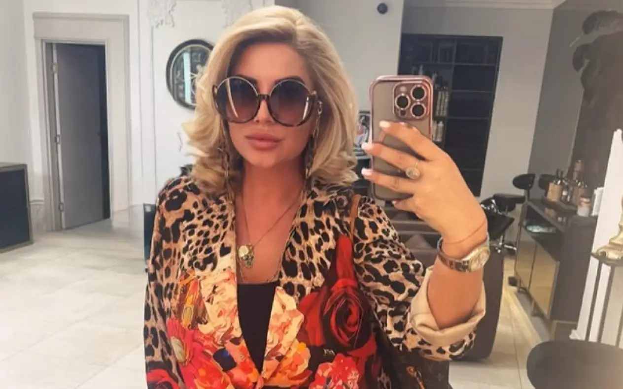 Dea Đurđević u studiju šarenom sakou i velikim naočarama za sunce pravi selfie u ogledalu
